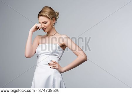 Bride In White Wedding Dress Standing With Hand On Hip And Crying Isolated On Grey