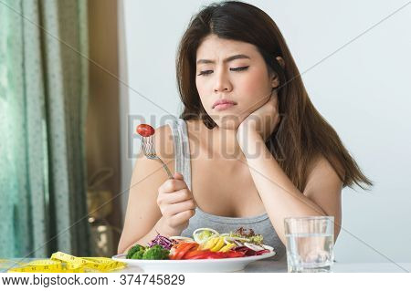 Asian Women Is On Dieting Time Looking At Tomato On The Fork. Girl Do Not Want To Eat Vegetables And