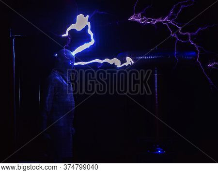 Huge Electric Coils Spew Lightning Striking A Man Dressed In A Chain Suit. Electric Show