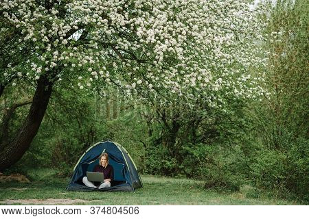 Woman Working On Laptop In Tent In Nature. Young Freelancer Sitting In Camp. Relaxing In Camping Sit