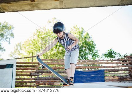 Skater Boy Rides On Skateboard At Skate Park Ramp. Kid Practising Skateboarding Outdoors On Skatepar