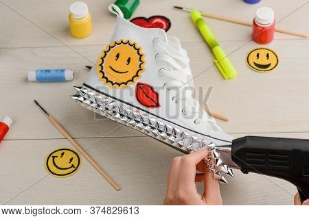 Designer Applying Metal Spikes Onto Outsole Of White Sneakers