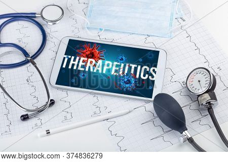 Tablet pc and doctor tools on white surface with THERAPEUTICS inscription, pandemic concept