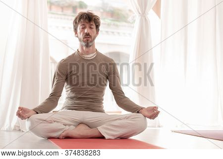 Yoga Teacher Sitting In The Lotus Position With Their Eyes Closed. Man Practicing Yoga. How To Keep