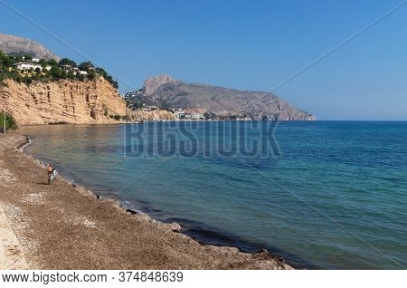 Altea, Costa Blanca, Spain - 30 September 2019: Man At Tranquil Stone Beach With Turquoise Colored O