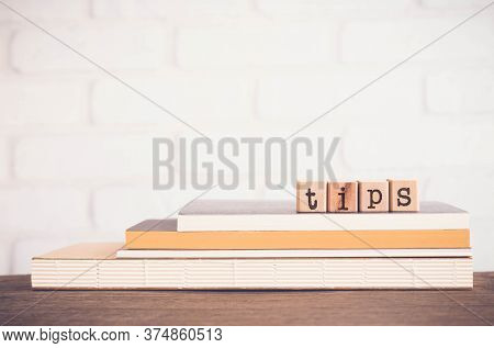 The Word Tips, Letters On Wooden Block Cubes On Top Of Books And Table With White Bricks Background,