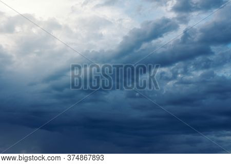 Dramatic Rainy Clouds On Dark Blue Stormy Evening Sky. Natural Background With Stormclouds And Sunli