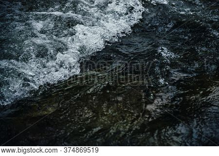 Nature Background Of Dark Water Stream Of Mountain River With Rapids. Full Frame Of Sea Surf. Natura