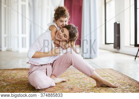 Young Smiling Mother Holding Little Pretty Daughter On Back Drea