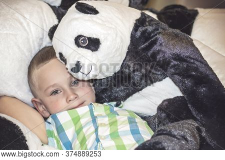 A Toy Panda Hugs A Boy With Wet Eyes. A Porter Of A Child Who Is Crying In A Toy Store. Close-up.