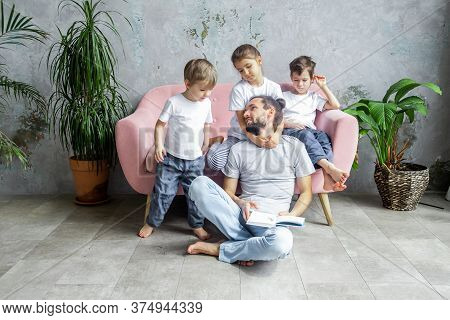 Cute Young Father Is Reading A Book To His Children. Happy Family Togetherness And Fatherhood. Child