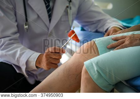 Doctor Using Trigonal Head Neurological Percussion Hammer On The Knee Area, To Check The Nervous Sys