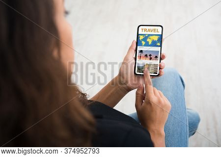 Unrecognizable Woman Using Smartphone With Opened Travel Website, Touching The Screen With Finger, O