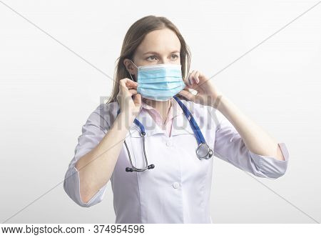 Female Doctor Surgeon Putting A Facial Mask On Standing With Stethoscope Isolated On White Backgroun