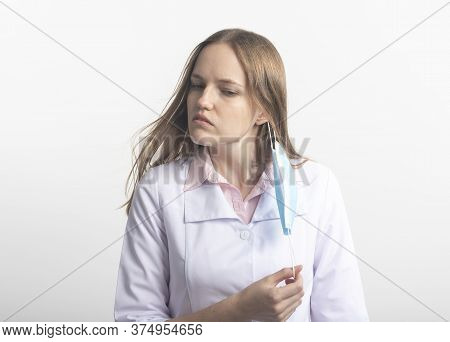 Tired Young Caucasian Female Doctor Put Off Her Mask After Hard Work Shift Isolated On White Backgro