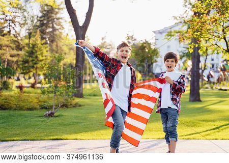 America's Usa Independence Day. Two Cute Brothers Guy Americans Standing In A City Park On Skateboar