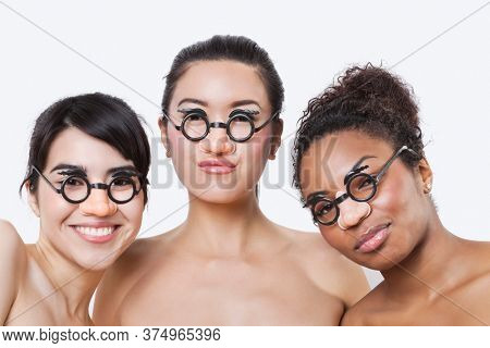 Portrait of young multi-ethnic women wearing groucho glasses over white background