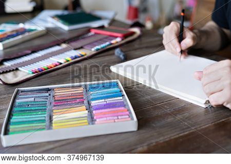 Man Painting With Pencil And Pastel Crayon Chalks On Paper. Box Of Pastel Chalks And Color Pencils O