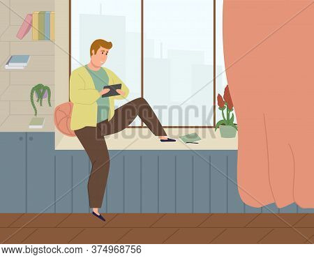 The Guy Works On A Tablet Or Phone Sitting On The Windowsill And Looking Out The Window At Home.