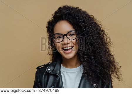 Headshot Of Cheerful African American Woman With Dark Curly Hair, Has Pleased Face Expression, Joyfu