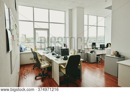 Interior of contemporary large office in modern center with desks, computer monitors, white leather armchairs and other stuff