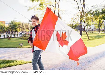 A Young Guy Of 9 Years Old Riding On A Sunny Road In The Evening In The City Park, Dressed In A Flan