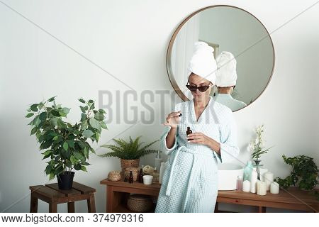 A Cute Young Woman Moisturizes Her Skin With Her Hylauron Serum In Her Bright Bathtub. A Girl In Sun