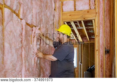 Man Installing Thermal Insulation Layer Under The Wall Using Mineral Wool With Fiberglass Cold
