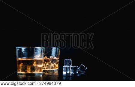 Whisky, Whiskey, Bourbon Or Cognac With Ice Cudes On Black Stone Table