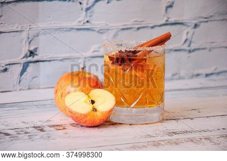 A Whole And Half-chopped Ripe Apple Stand On A Table Near A Crystal Glass Of Siber With Cinnamon And