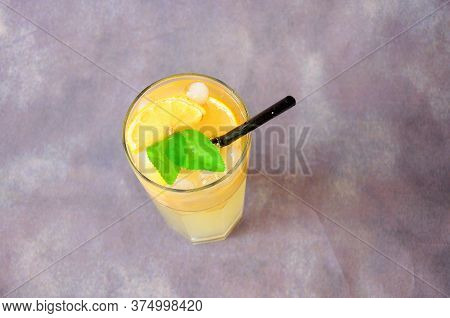 Tall Glass Cup Of Lemon Mojito With Ice, Mint Leaves And Slices Of Citrus On A Gray Background.