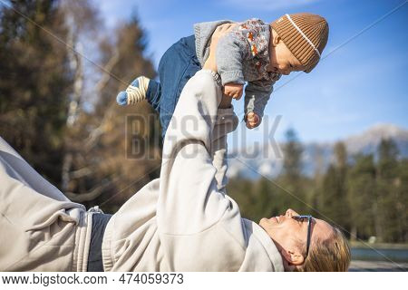 Happy Family. Young Mother Playing With Her Baby Boy Infant Oudoors On Sunny Autumn Day. Portrait Of