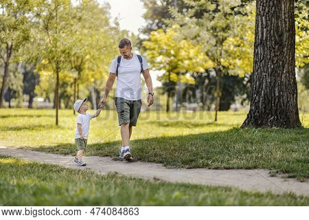 Happy Childhood. Father And Son Walking Through The Woods On A Sunny Summer Day. Dad Holds His Son's