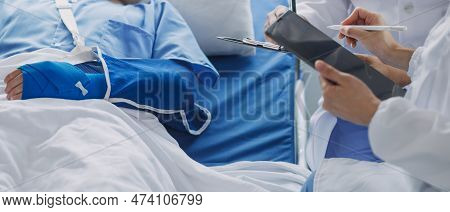 Injured Patient Showing Doctor Broken Wrist And Arm With Bandage In Hospital Office Or Emergency Roo