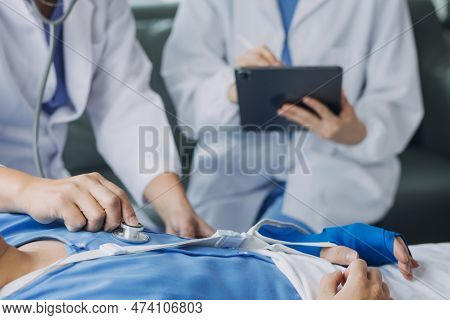 Injured Patient Showing Doctor Broken Wrist And Arm With Bandage In Hospital Office Or Emergency Roo