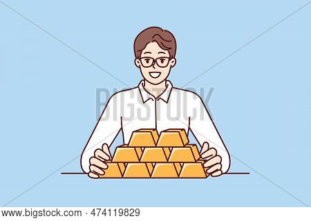 Businessman With Gold Bars Sitting At Table And Smiling Looking At Camera For Precious Metals Invest