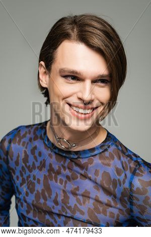Portrait Of Stylish And Joyful Pangender Person With Makeup And Nose Piercing Isolated On Grey.