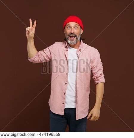 Positive European Caucasian Man Handsome Shows Gesture Of V Victory. Cheerful Man With Silver Beard 