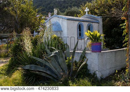 Blue Chapel With A Cross And Angel On The Roof, Built In A Beautiful Small Garden At The Coast. Kini