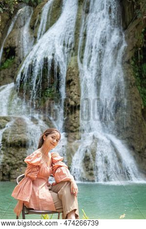 Young Asian Woman Sitting On A Chair In Front Of The Khoun Moung Keo Waterfall