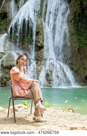 Young Asian Woman Sitting On A Chair In Front Of The Khoun Moung Keo Waterfall