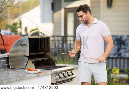 Man Cooking Meat On Barbecue In The Backyard Of The House. Handsome Man Preparing Barbecue. Barbecue
