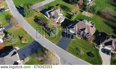 Quiet Residential Street In Suburban Neighborhood With Large Single-family Houses, Evergreen Trees,