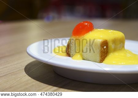 Close Up Of Bread Pudding With Lemon Sauce And Cherry Topping.
