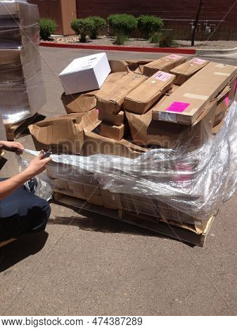 Cutting Shrink Wrap On A Pallet Of Boxes Outside