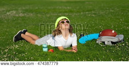 Kid Boy Girl Resting On Green Grass. Kids Relaxation. Child Laying In Grass In The Park. Summer Holi