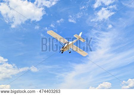 Single Engine Ultralight Plane Flying In The Blue Sky With White Clouds
