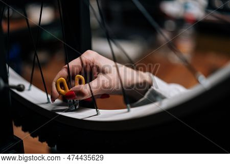 Close-up Cropped Shot Of Unrecognizable Female Cycling Repairman Hands Checking Bicycle Wheel Spoke 