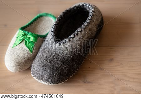 Unpaired Mens And Womens Home Shoes Made Of Dried Wool Stand On A Wooden Floor