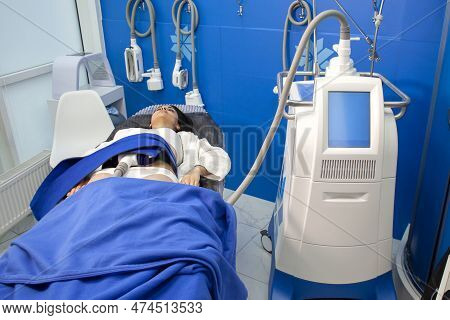 Coolsculpting Procedure In Cosmetology Clinic, The Girl Patient Lies On The Couch Connected To The M